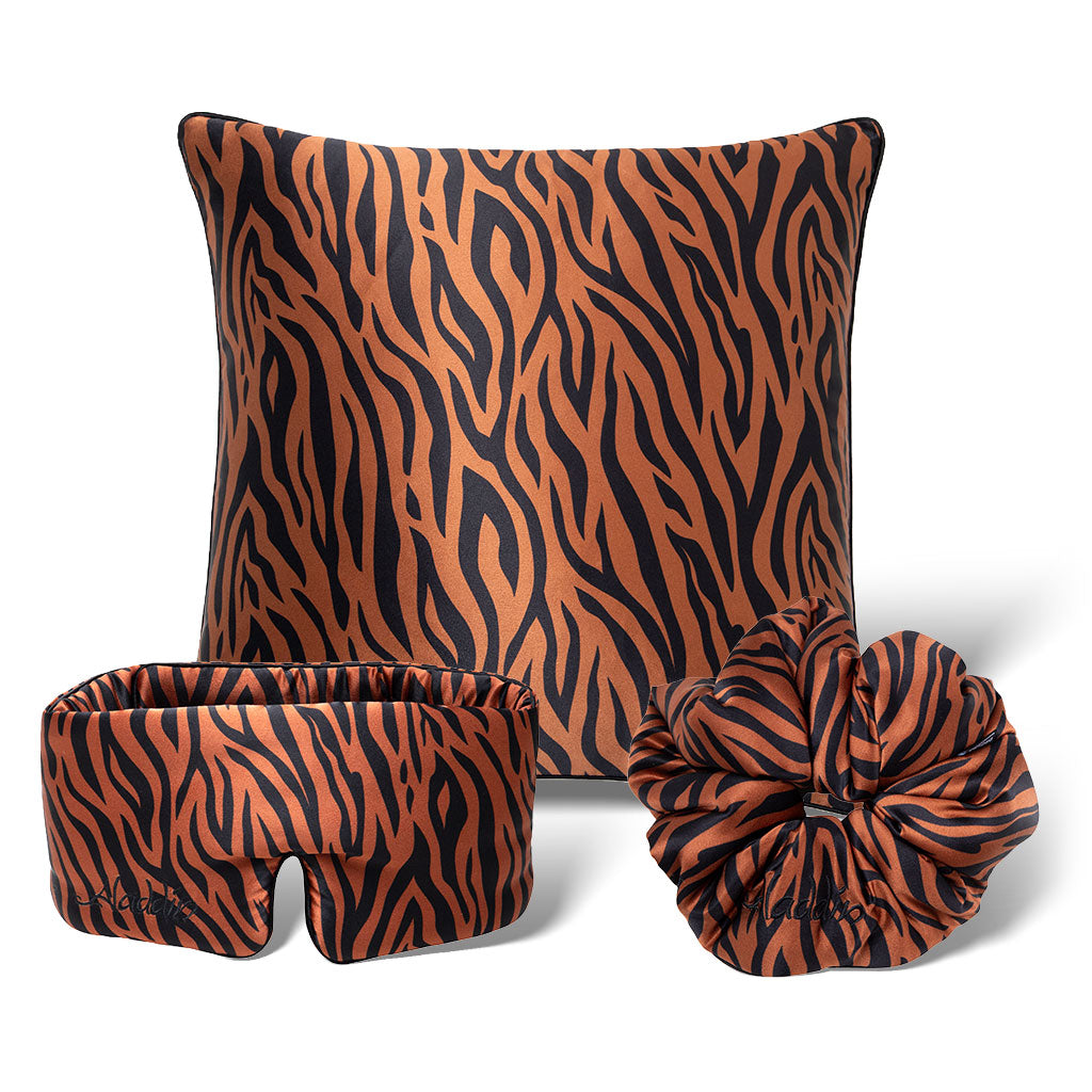 The Rajah Bundle by drowsysleepco features a black and orange tiger stripe square pillow, sleep mask, and scrunchie, all arranged on a white background.