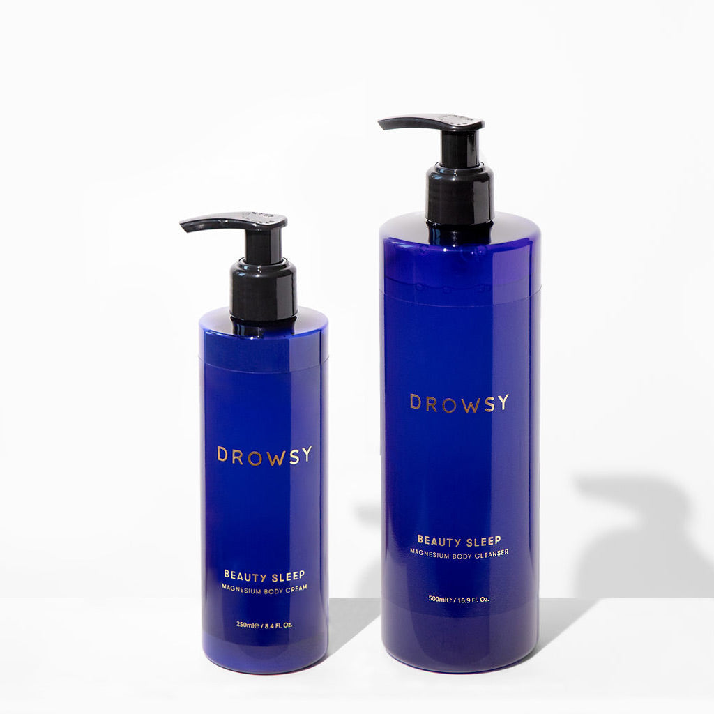 Two blue pump bottles from drowsysleepco’s Beauty Sleep Bundle—a magnesium-infused body cream (smaller) and body wash (larger)—are set against a white background.