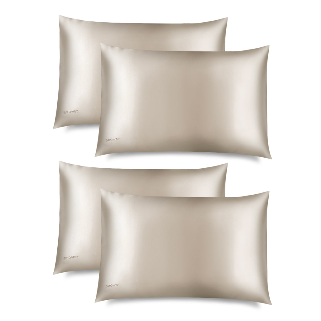 Four Dusty Gold Silk Pillowcases with a subtle sheen is displayed on a white background. DROWSY appears in small letters at the bottom left—a hair-protecting, skincare-essential silk pillowcase.