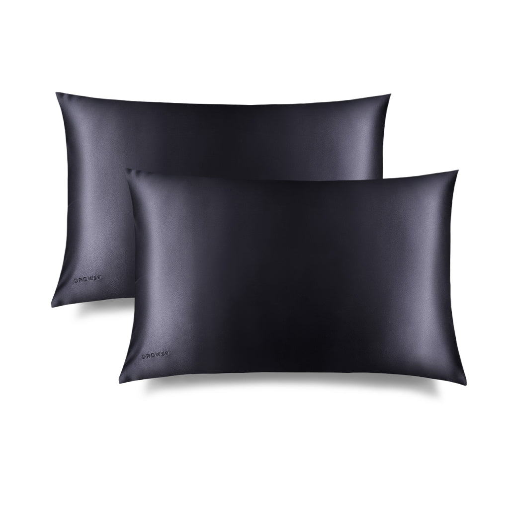 Two drowsysleepco Moonlight Shadow Silk Pillowcases are shown overlapping on a white background, each with a smooth, shiny black finish and small corner logo—an essential hair-protecting, skin-friendly addition to your beauty routine.