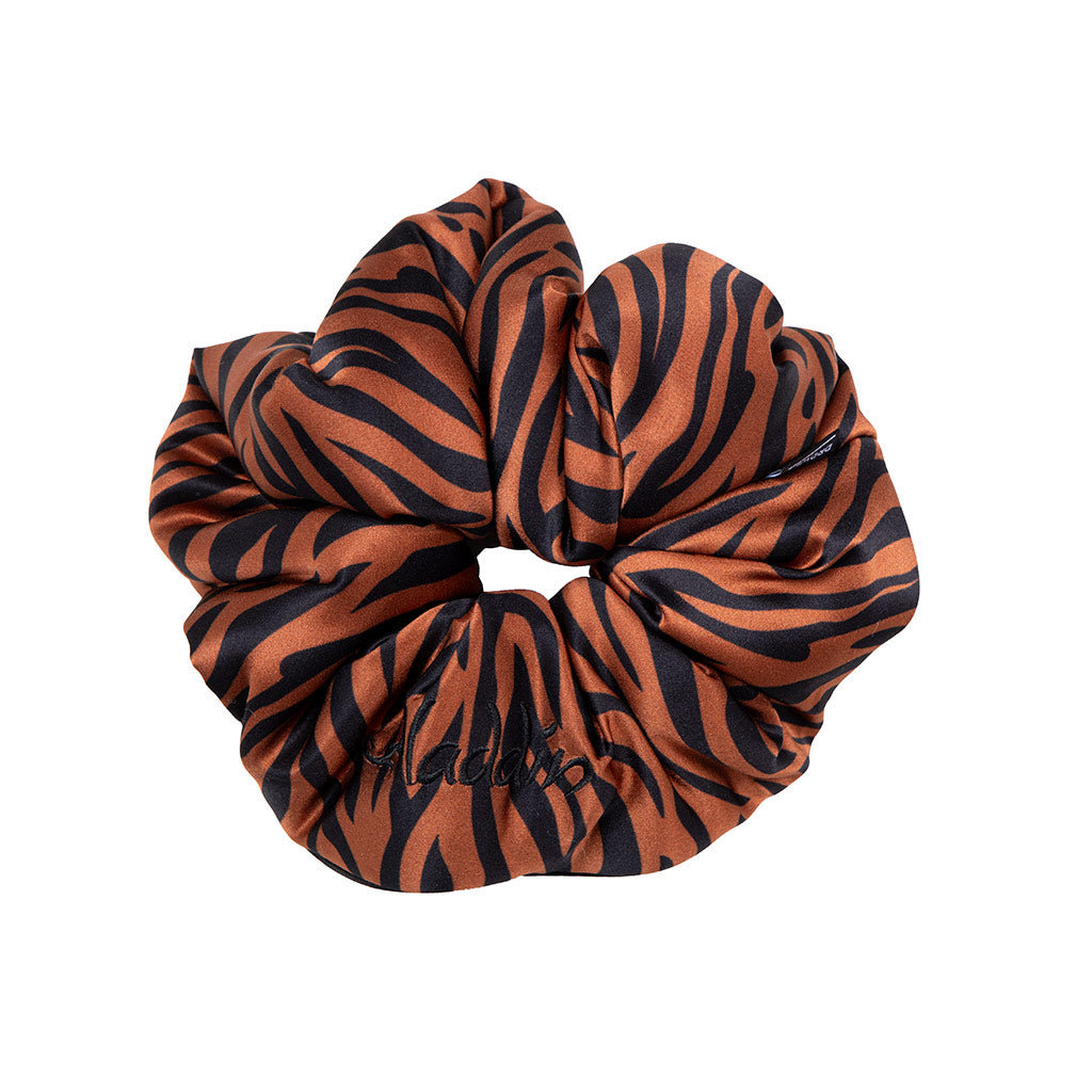 The Rajah Padded Scrunchie by drowsysleepco is an oversized silk hair accessory in black and orange tiger stripes, with "Malibu" embroidered in black—ideal for stylish hair protection.