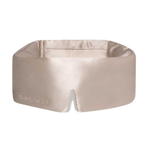 The Dusty Gold sleep mask by drowsysleepco is a beige silk blackout eye mask with a wide, padded design and small bottom notch—ideal for uninterrupted beauty sleep.