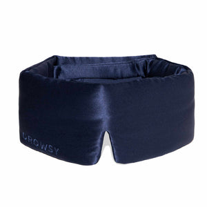 The Midnight Blue sleep mask by drowsysleepco features thick, padded sides and DROWSY embroidery on the front. Made from dark blue mulberry silk, it is designed to block out light completely for restful sleep.