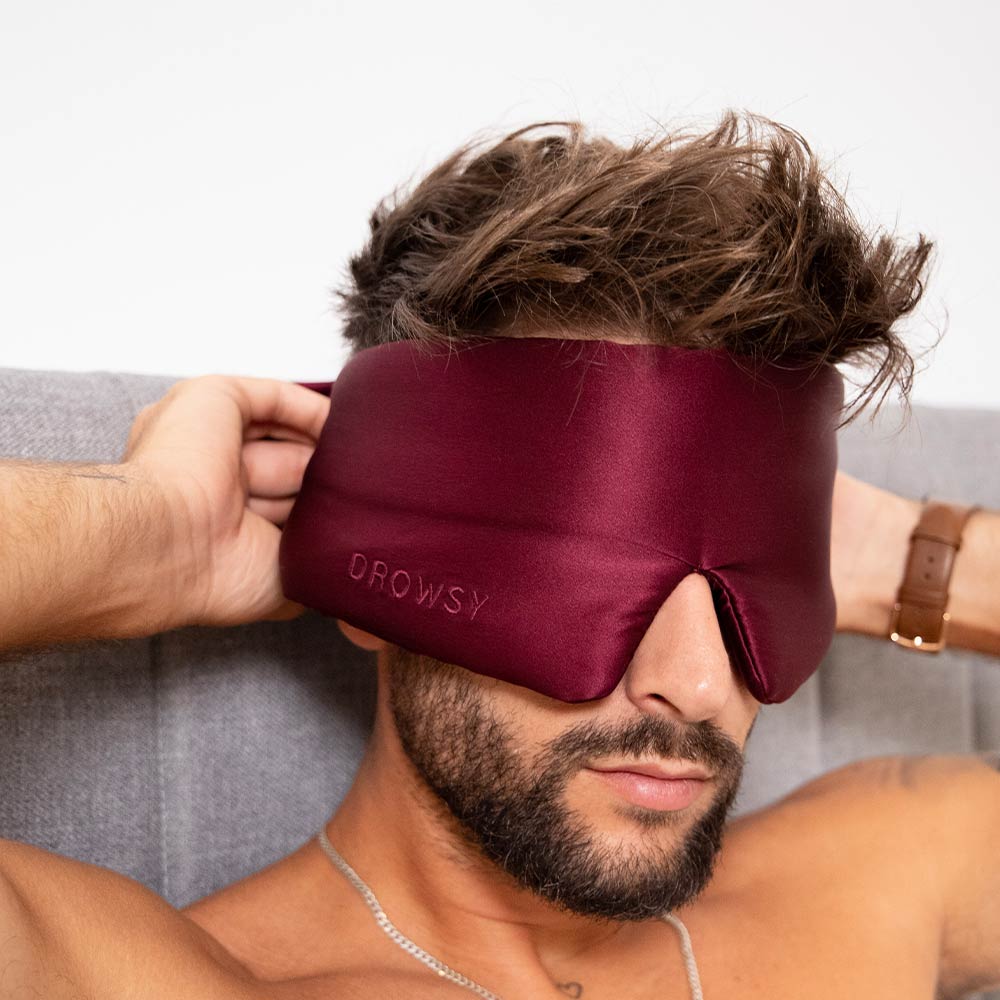 Male model covering eyes with rouge coloured Drowsy silk sleep mask