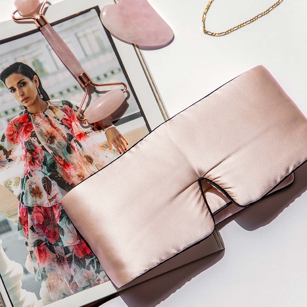 Light pink Drowsy silk sleep mask on top of a beauty magazine