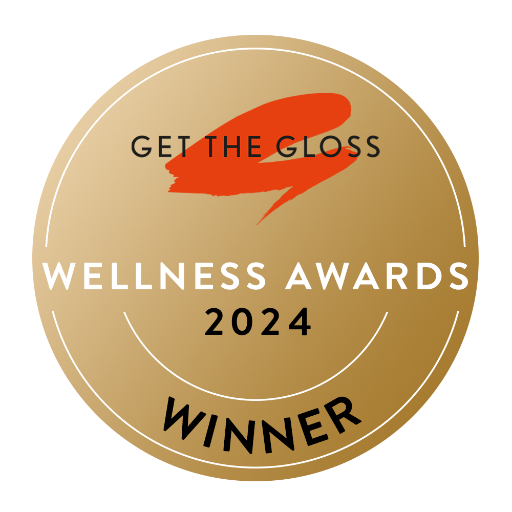 A gold circular badge with GET THE GLOSS and an orange brushstroke at the top, WELLNESS AWARDS 2024 in the center, and WINNER at the bottom.