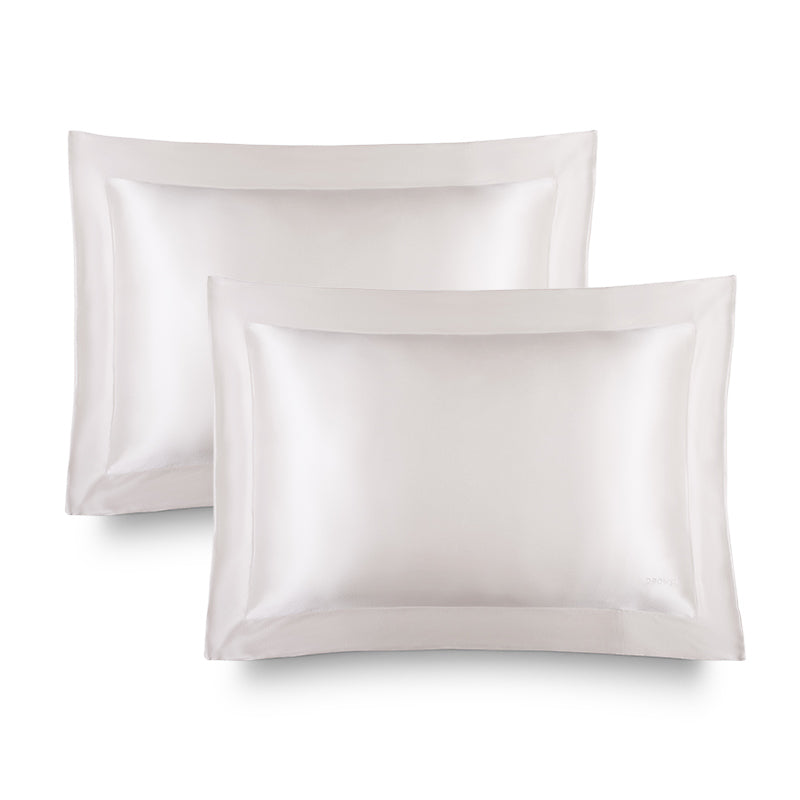 Two Hyalo Pillowcases – Akoya Pearl by us.drowsysleepco, crafted in lustrous white silk with a shiny, smooth texture, are neatly stacked and slightly overlapping against a clean white background—perfect for boosting overnight hydration and supporting your skin’s natural moisture balance, just like hyaluronic acid.