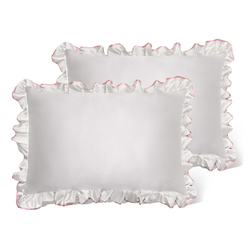 Two "Sleep and the City - Pearl & Pink Pillowcase" by drowsysleepco, featuring white fabric with ruffled satin edges and a pink trim, are placed slightly overlapping on a plain white background.