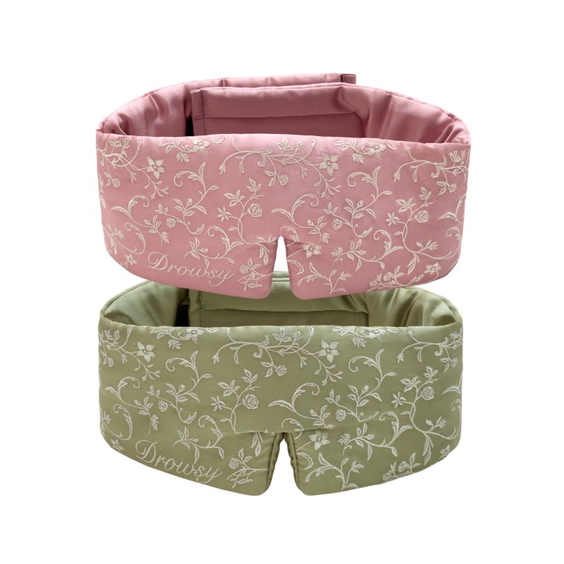 Two Pride & Prejudice - Sage + English Rose Sleep Masks in padded silk with white floral patterns, one in sage green and one in dusty rose.