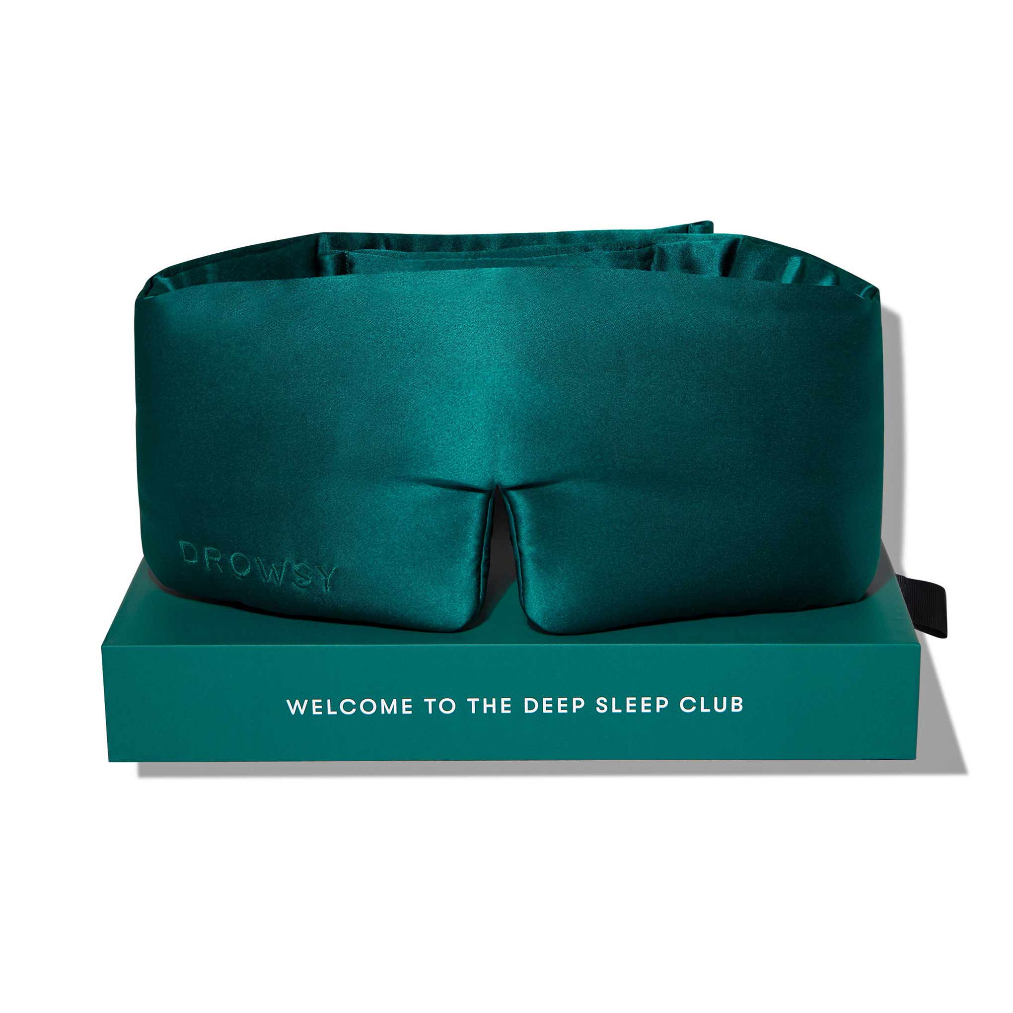 The Green Sapphire silk sleep mask by drowsysleepco, featuring the brand name on the side, rests on a matching box labeled WELCOME TO THE DEEP SLEEP CLUB—your ultimate blackout eye mask for beauty sleep.