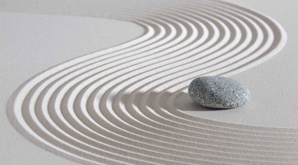 Sand with a zen curve pattern raked into it and a pebble.