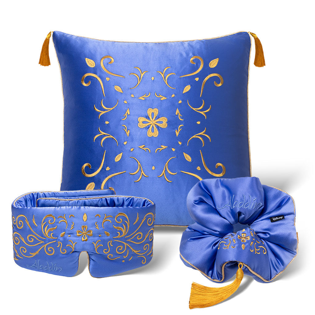 The drowsysleepco Magic Carpet Bundle features a blue satin pillow, eye mask, and scrunchie with gold floral embroidery and tassels, inspired by Disney’s Aladdin, shown on a white background.