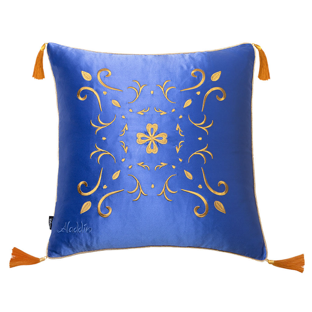 The Magic Carpet Cushion Cover by drowsysleepco features royal blue fabric with gold embroidered florals, orange tassels on each corner, and "Aladdin" stitched in white—perfect for adding a touch of luxury to your bedroom.