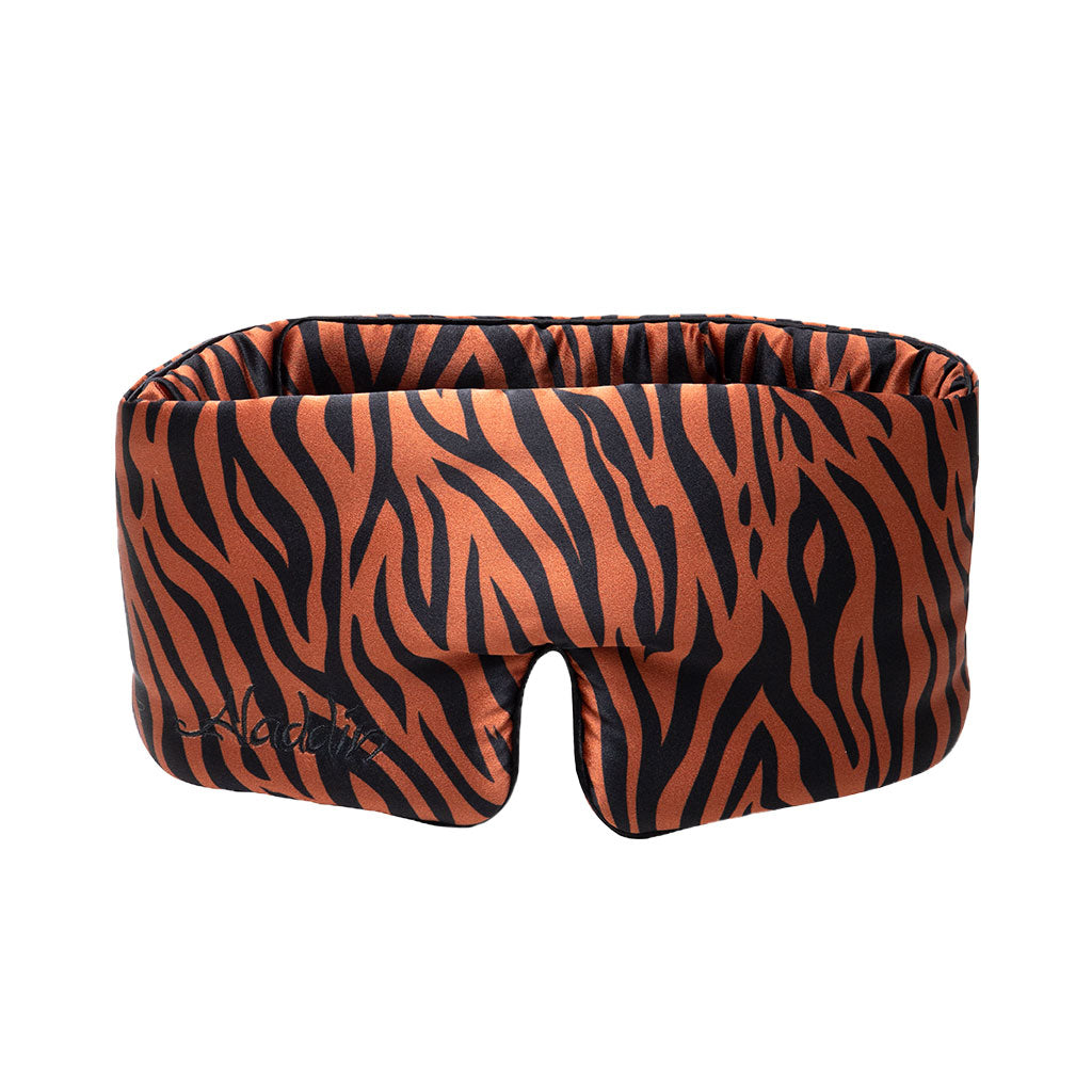 The Rajah Sleep Mask by drowsysleepco is a wide, padded silk mask with orange and black tiger stripes, a contoured shape, and a nose cutout for added comfort.
