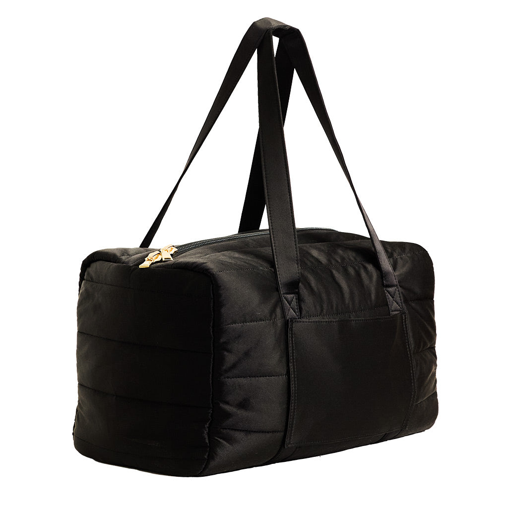 The Drowsy Silk Weekender - Black Jade by Drowsy is a black quilted duffel bag featuring two long handles, a gold zipper, and an exterior pocket, shown against a white background—ideal as a stylish travel or weekend bag for your next getaway.