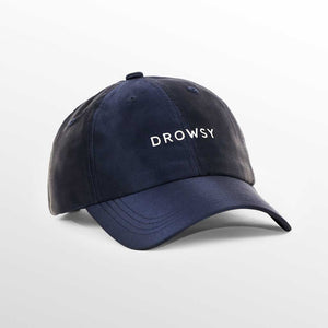 The Drowsy Silk Cap - Midnight Blue by Drowsy features white embroidered lettering on the front—perfect for outdoor workouts or keeping your hair flawless. Shown here against a simple, light background.