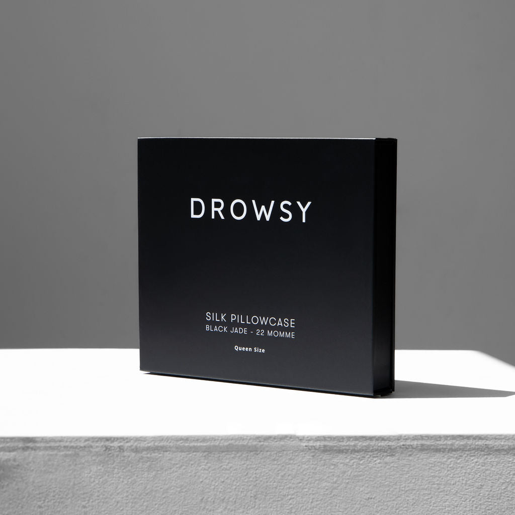 Slim black Drowsy pillowcase box on a white stand with a grey background