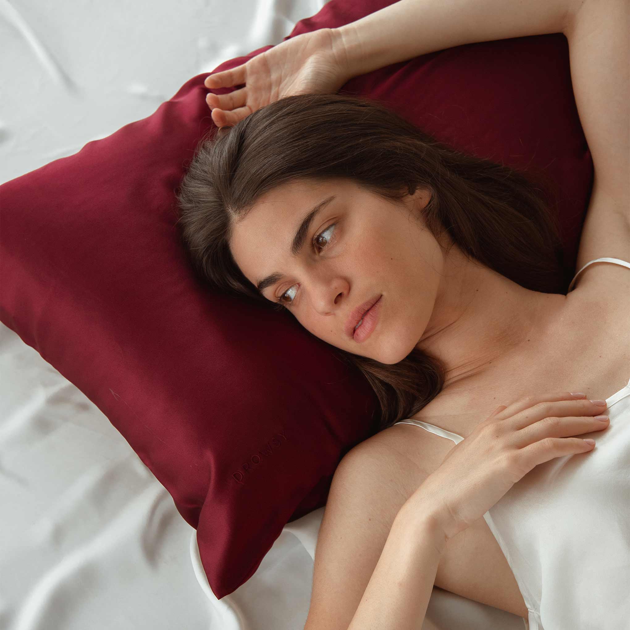 Model lying on a rouge coloured Drowsy silk pillowcase