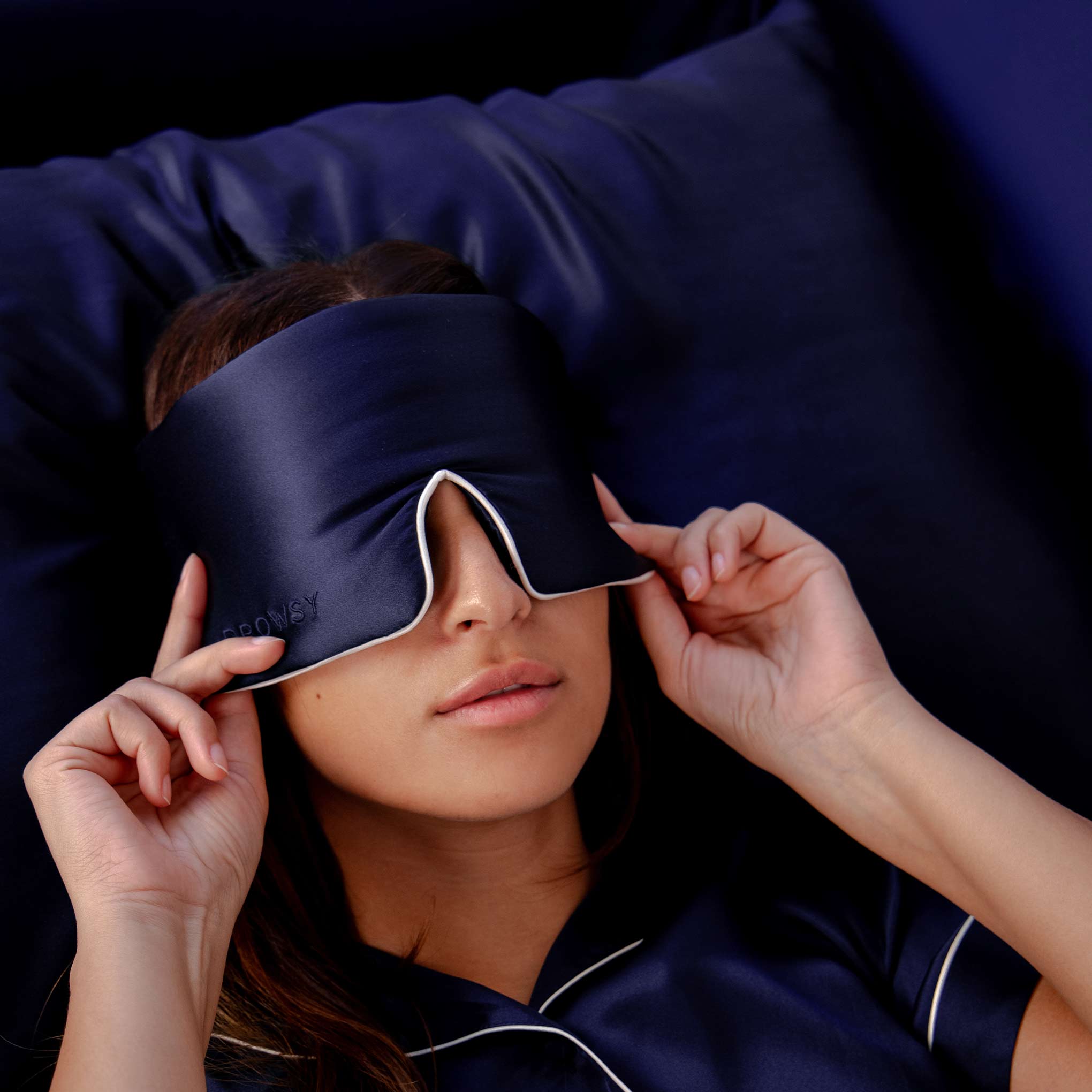 Girl sleeping on blue silk pillowcase with Drowsy Sleep Co. Sleep mask over eyes