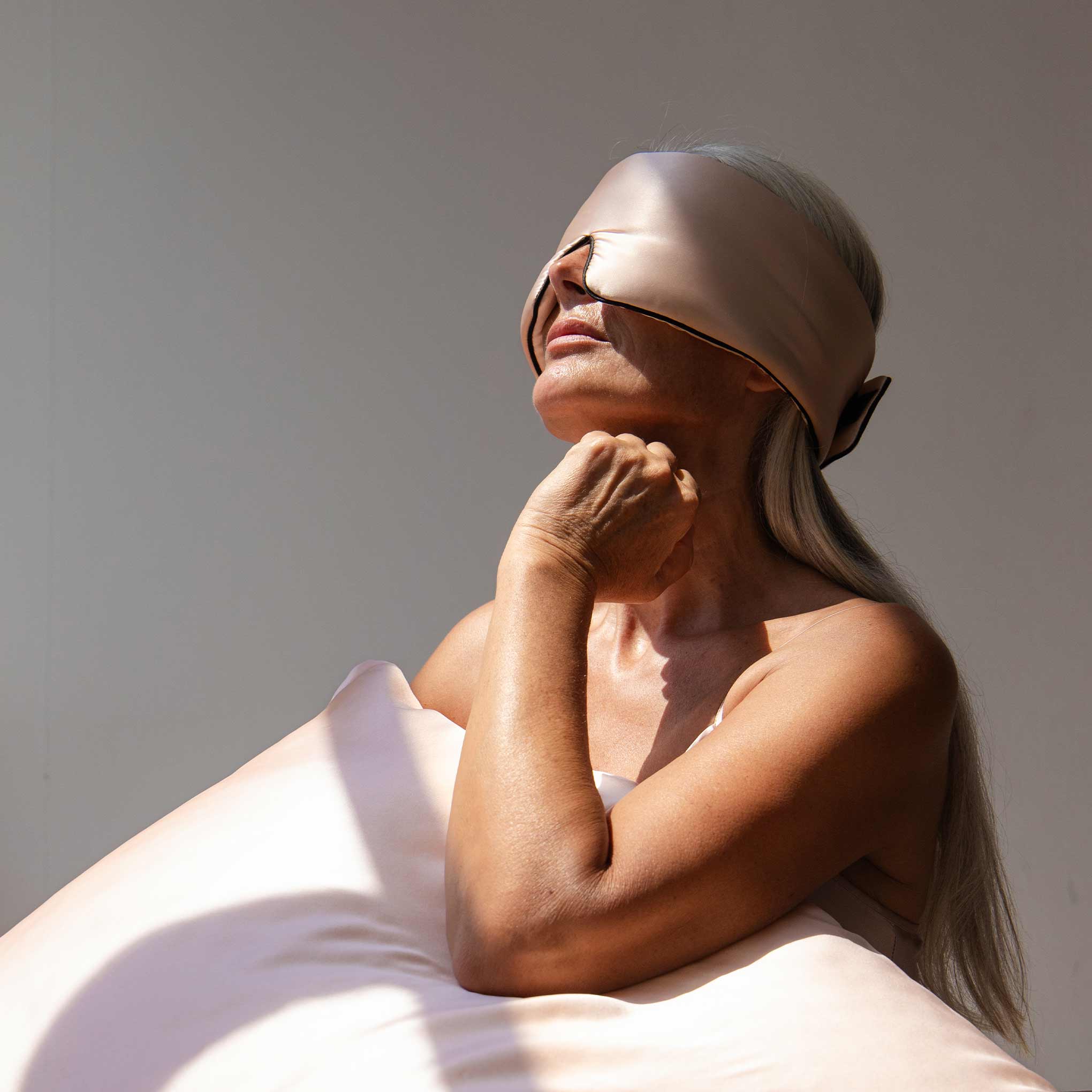 model with a light pink silk sleep mask covering her eyes