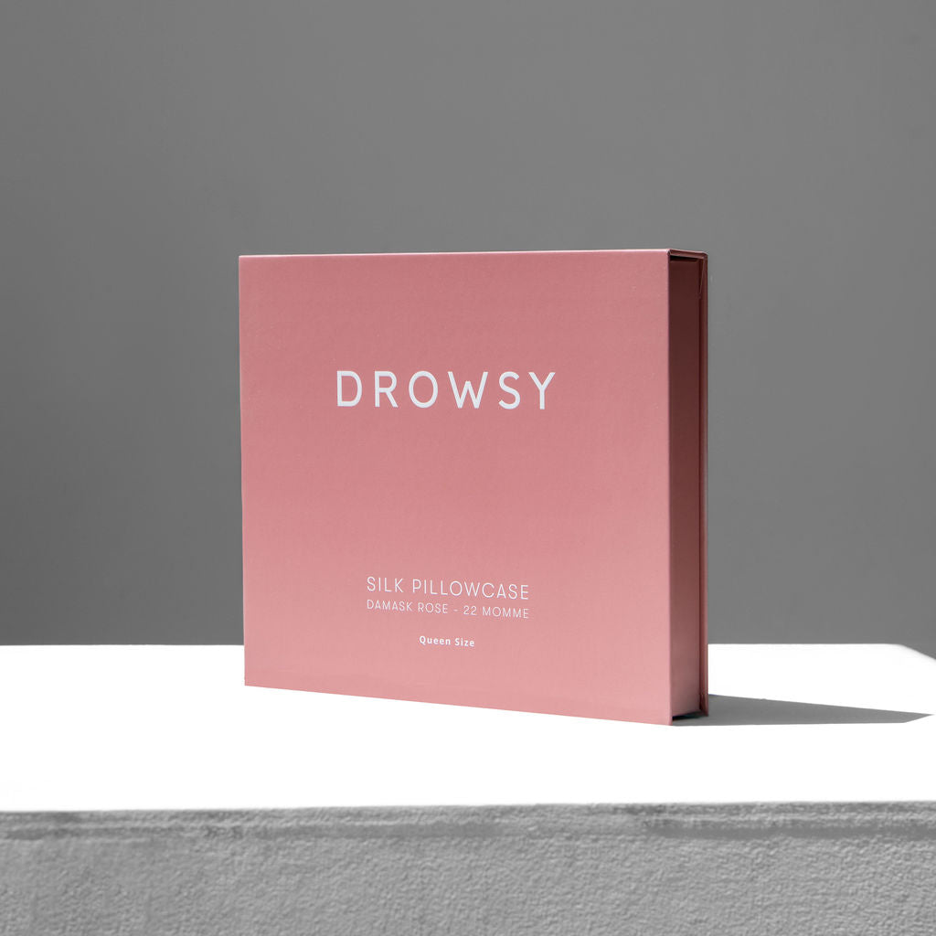 Pink Drowsy silk pillowcase box on a white stand with a grey background