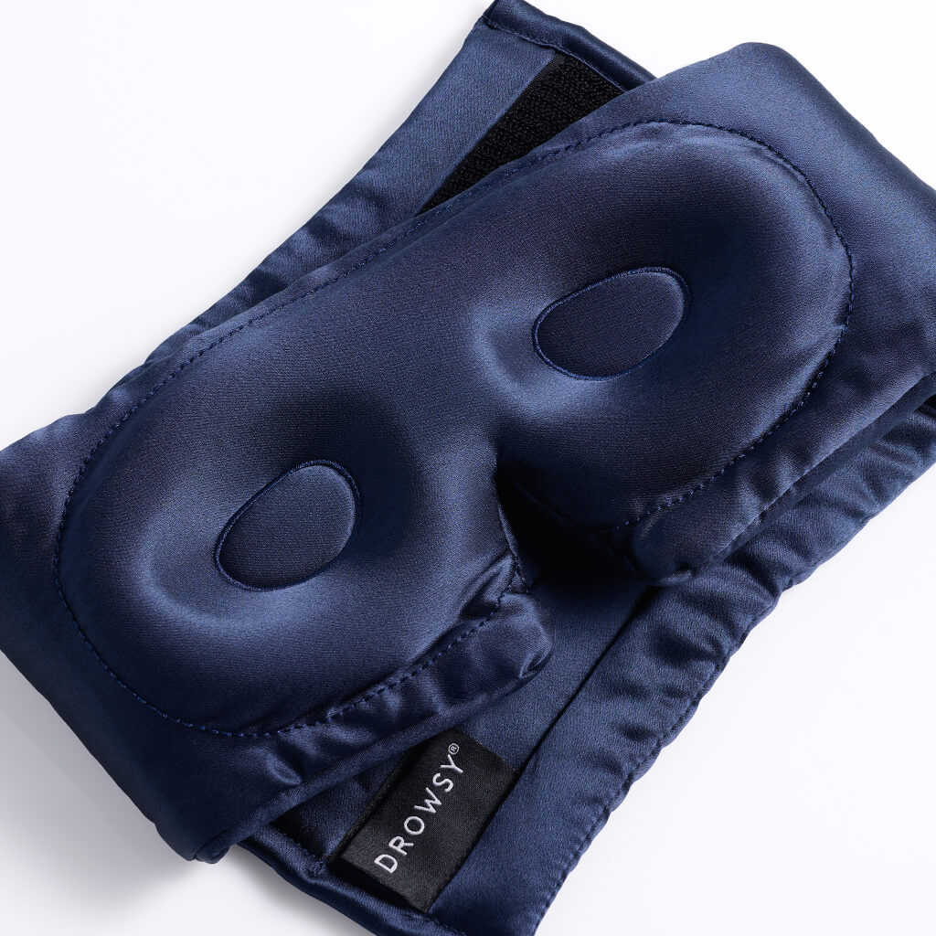 The Drowsy RevitaLash® Cosmetics x Drowsy® Dream Lashes Kit features a dark blue padded silk sleep mask with an elastic strap and Drowsy label, ideal for protecting your lashes while using your favorite eyelash conditioner.