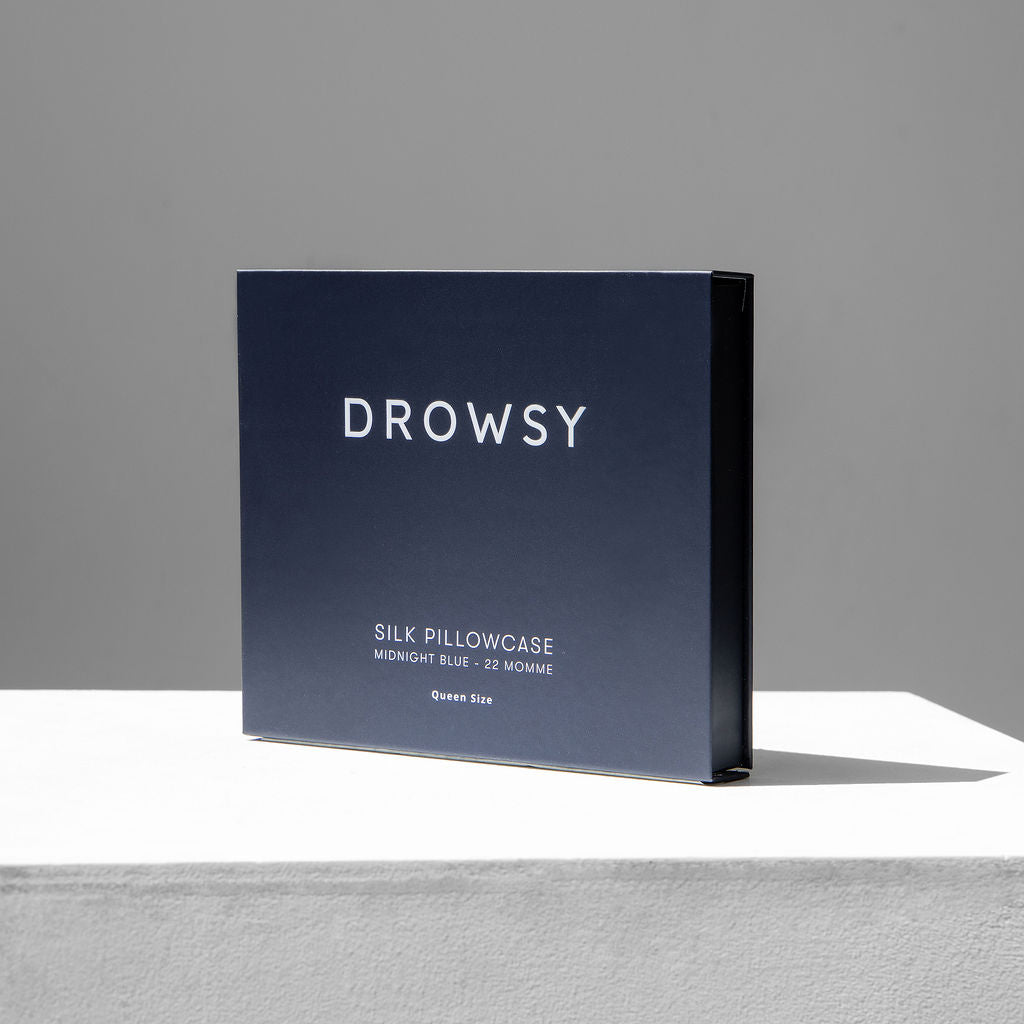 Blue Drowsy silk pillowcase box on a white stand with a grey background