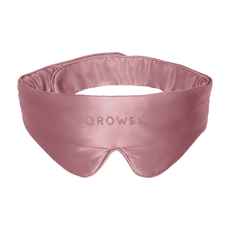 The Damask Rose Featherweight Silk Sleep Mask by drowsysleepco is a silky pink mulberry silk mask designed to cover your eyes and block out light for better sleep, featuring the word “DROWSY” embroidered on the front.