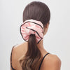 A woman with long brown hair in a low ponytail, secured by the drowsysleepco Sleep and the City Pink Padded Scrunchie, wears a black spaghetti strap top, photographed from behind against a plain background.