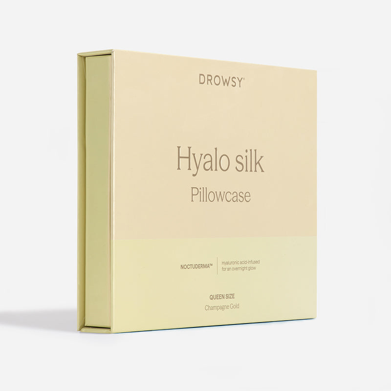 A pale yellow box labeled “Hyalo Pillowcase - Champagne Gold” from us.drowsysleepco, featuring information about its hyaluronic acid infusion and a Queen Size Champagne Gold note on the front, set against a white background.